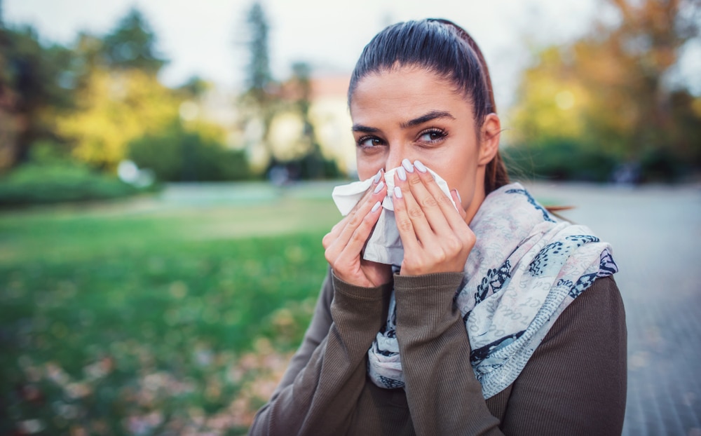 Woman blowing her nose outside